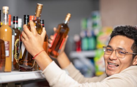 Man looking at camera while buying bottles of alcohol