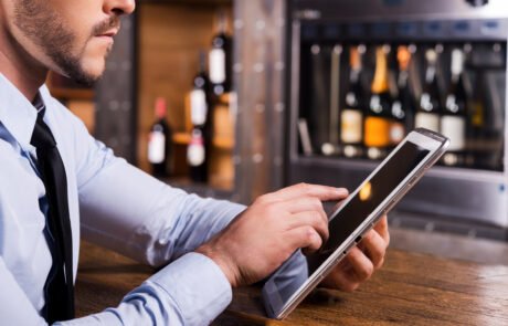 Surfing web in bar. Close-up of man in shirt and tie working on digital tablet while sitting at the bar counter